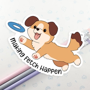 May include: A sticker showing a cartoon corgi dog jumping for a blue frisbee. The dog is brown and tan with a joyful expression. The sticker has the text "making Fetch Happen". Pencils are in the background.
