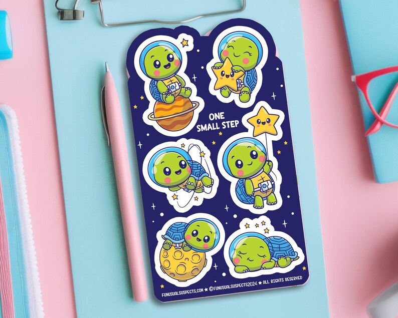 May include: A set of six colorful stickers featuring cute cartoon turtles in space. The stickers are on a blue background with stars and planets. The text "One Small Step" is printed on the stickers.