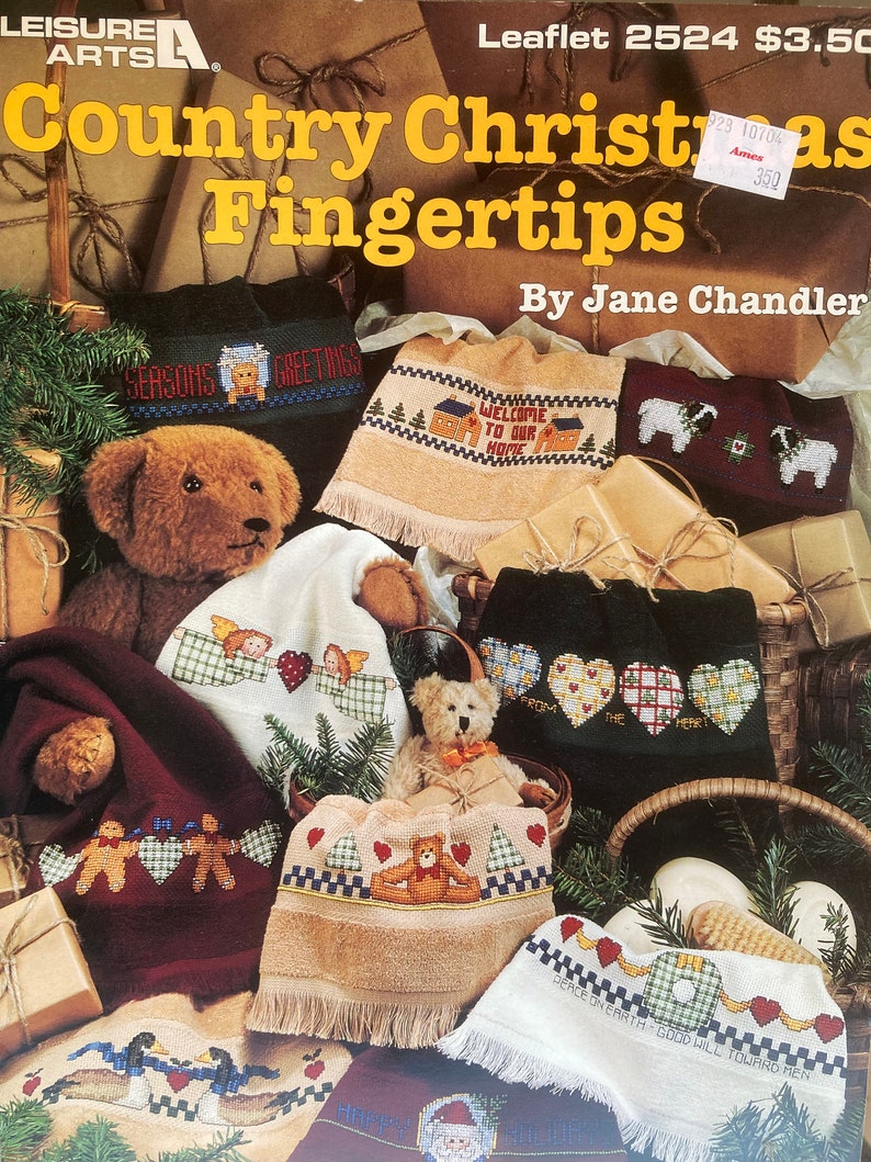 Puede incluir: Una colecci&oacute;n de patrones de punto de cruz para toallas de dedos de Navidad de estilo r&uacute;stico. Los patrones presentan una variedad de dise&ntilde;os, incluyendo un oso de peluche, un hombre de jengibre, un &aacute;rbol de Navidad y una corona. Los patrones est&aacute;n impresos sobre un fondo marr&oacute;n con texto blanco. El texto de la portada dice "Country Christmas Fingertips" y "By Jane Chandler".