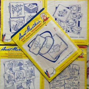 May include: Several vintage Aunt Martha's Hot Iron Transfer packets. The packets are yellow with blue and white designs, featuring motifs for tea towels and fine chinaware. Text includes "Each Design Good For Several Stampings."