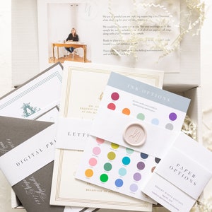 May include: A sample wedding invitation kit with a variety of paper options, ink colors, and envelope styles. The kit includes a note from the company, "Workman Creative Co.", thanking the customer for their order.