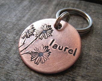 May include: Copper dog tag with a floral design and the name "Laurel" engraved on it.