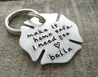 May include: Silver firefighter helmet keychain with the text "make it home safe. i need you" and a heart symbol, followed by the name "bella".
