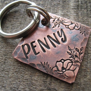 Puede incluir: Chapa de perro de cobre con acabado martillado y dise&ntilde;o floral. La chapa est&aacute; grabada con el nombre "PENNY".