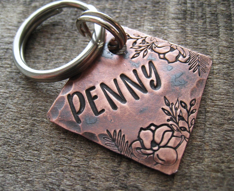 Puede incluir: Chapa de perro de cobre con acabado martillado y dise&ntilde;o floral. La chapa est&aacute; grabada con el nombre "PENNY".