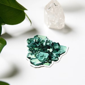 May include: A green crystal sticker with a white border. The sticker is shaped like a cluster of crystals and is on a white background.
