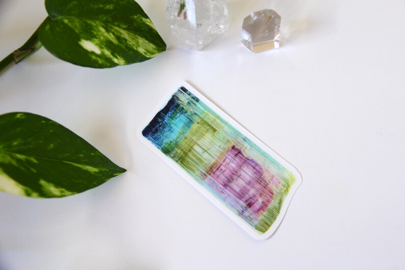 May include: A colorful abstract sticker with vertical lines in shades of blue, green, yellow, pink, and purple. The sticker has a white border and is on a white background.