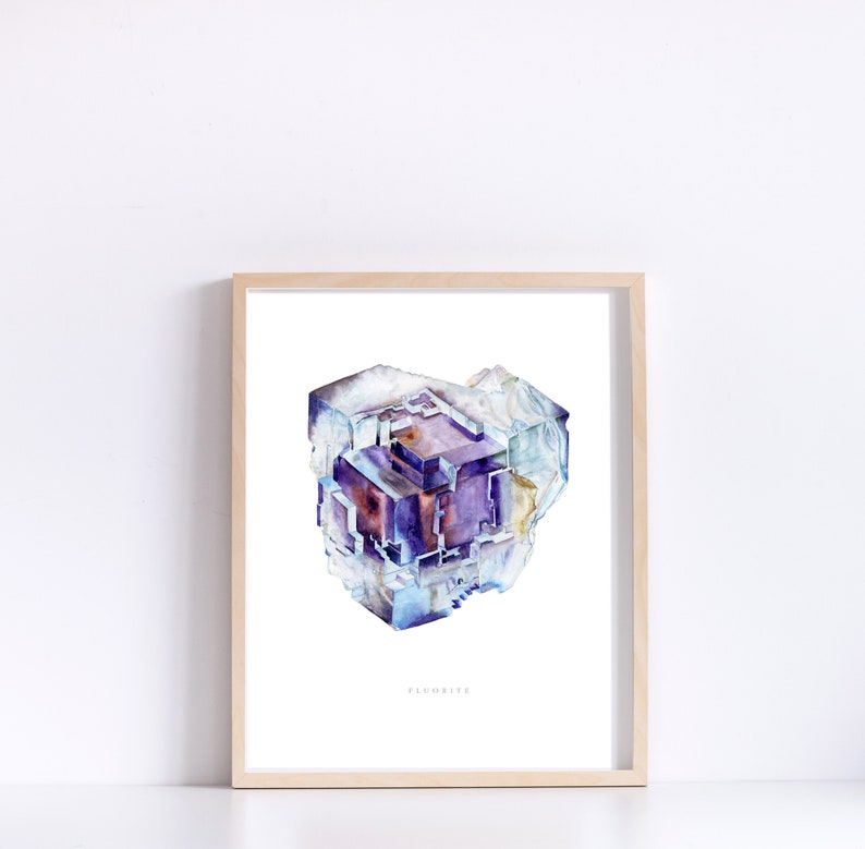 May include: A watercolor painting of a fluorite crystal. The crystal is a deep purple color with hints of blue and white. The painting is framed in a light wood frame and has the word "Fluorite" written below the crystal.