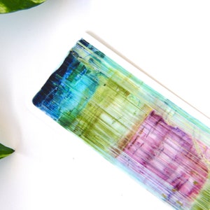 May include: A rectangular ceramic dish with a colorful abstract design. The design features vertical stripes of blue, green, yellow, and pink.