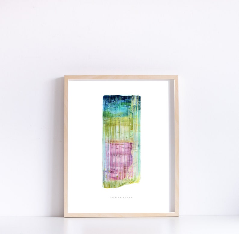 May include: A watercolor painting of a tourmaline crystal. The crystal is a vibrant mix of green, blue, pink, and yellow. The painting is framed in a light wood frame and has the word "Tourmaline" written below the crystal.