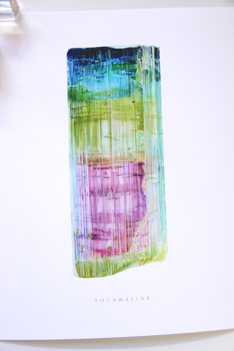 May include: A watercolor painting of a tourmaline crystal. The crystal is a long, rectangular shape with a variety of colors, including green, blue, pink, and purple. The crystal is surrounded by a white background with the word "TOURMALINE" printed below it.