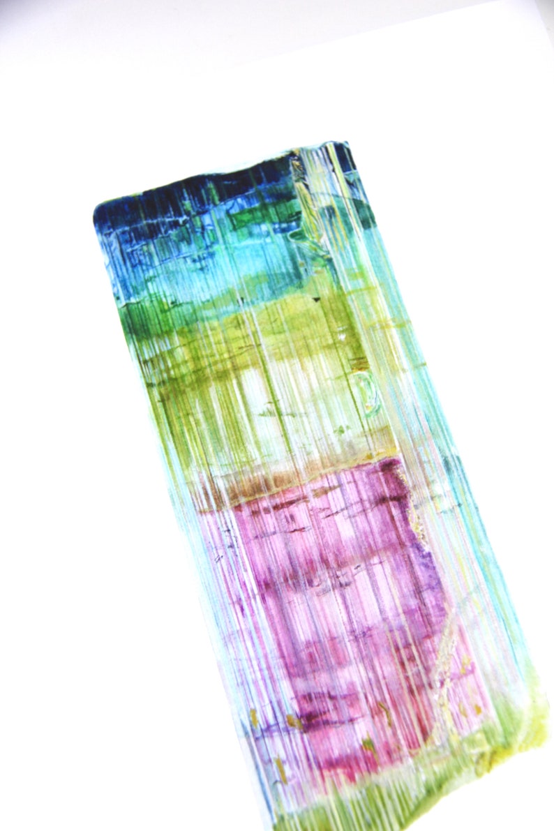 May include: A close-up of a multi-colored crystal with shades of blue, green, purple, and yellow. The crystal has a striated texture and is translucent.