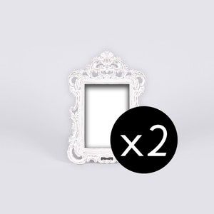 May include: Set of two white ornate picture frames with a decorative design. The frames are empty and ready to display photos or artwork.