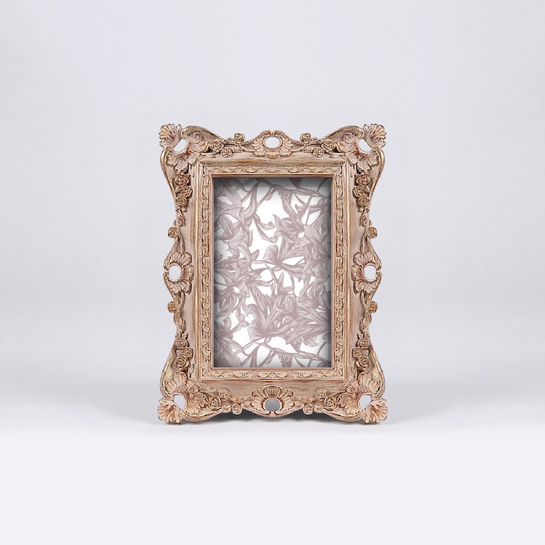 May include: A vintage-style, ornate wooden picture frame with a floral pattern inside. The frame is a light brown color with a distressed finish.
