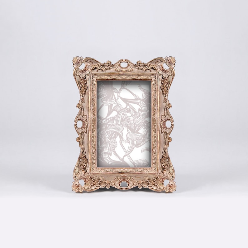 May include: A decorative, ornate, wooden picture frame with a light brown finish. The frame has a floral design inside the glass.