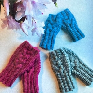 May include: Three pairs of knitted fingerless gloves in different colors: blue, gray, and pink. The gloves have a cable knit pattern.