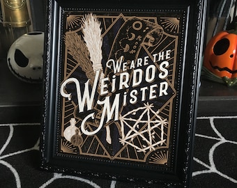 Könnte beinhalten: Ein schwarzer gerahmter Druck mit goldenem Hintergrund und schwarzer Schrift. Der Druck zeigt einen Besen, eine Schriftrolle und ein Pentagramm. Der Text lautet "We are the Weirdos Mister".