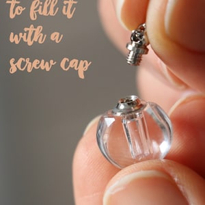 Könnte beinhalten: Ein klarer, kugelförmiger Glasflakon mit silbernem Schraubverschluss, gehalten zwischen Fingern. Der Flakon hat eine kleine Öffnung zum Befüllen. Der Text "so easy to fill it with a screw cap" ist sichtbar.