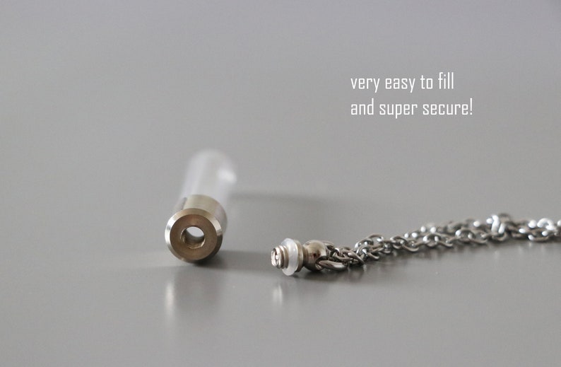 May include: A clear glass vial with a silver-colored metal cap and a matching chain. The vial is open, with the chain detached. Text in the image reads: "very easy to fill and super secure!"