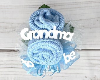 May include: A blue sock flower bouquet with a white tulle bow and the words "Grandma to be" in white letters.