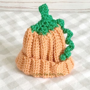 Peut inclure: Un bonnet en crochet en forme de citrouille pour b&eacute;b&eacute;. Le bonnet est orange avec une tige et des feuilles vertes. Le bonnet est fait d'un fil doux et est parfait pour l'automne.