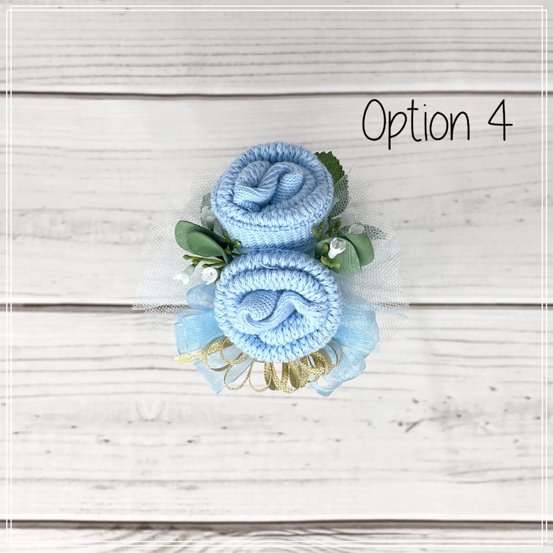 May include: Two light blue baby socks rolled into the shape of roses with green leaves and white tulle. The text "Option 4" is in the top right corner of the image.