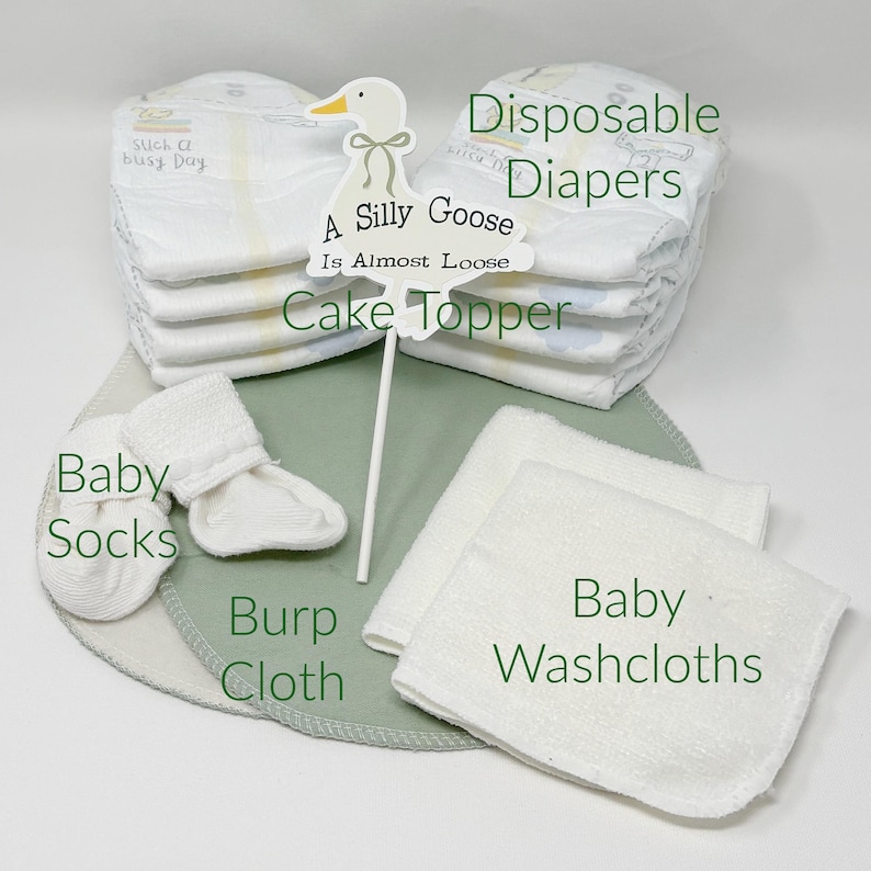 May include: A collection of baby essentials, including disposable diapers, baby socks, washcloths, and a burp cloth. A cake topper with a goose design and the text "A Silly Goose Is Almost Loose" is also included. The items are arranged on a light green surface.