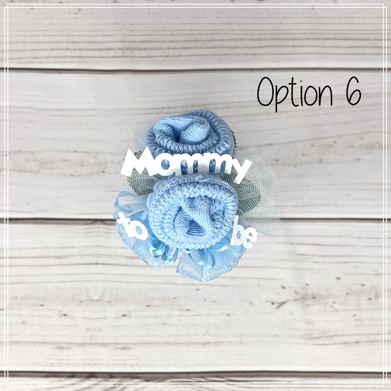 May include: A blue sock flower bouquet with white tulle and the text "Mommy to be".