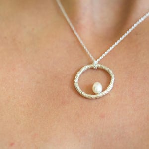 Zarte Perlenkette. Kleine Perle aus natürlichem Süßwasser auf einem strukturierten Kreis aus Sterlingsilber. Runder Anhänger mit Perle. Bild 7