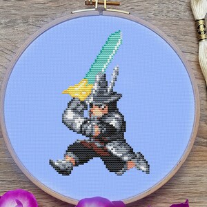 May include: A cross-stitch embroidery hoop with a blue background and a pixelated image of a character holding a sword. The character is wearing a black hat and a gray coat. The embroidery hoop is surrounded by flowers.