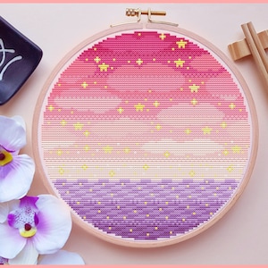 May include: A pink, yellow, and purple ombre embroidery hoop with a design of yellow stars on a pink background and yellow dots on a purple background.