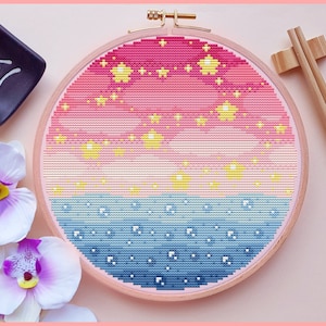 May include: A round embroidery hoop with a pink, yellow, and blue gradient design. The design features a scattering of yellow stars.
