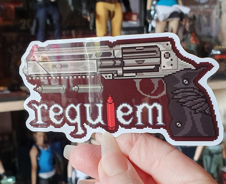 以下が含まれることがあります： 白い文字で「requiem」という言葉が入った、ピクセル化されたリボルバーのデザインのステッカー。銃は銀色とグレーで、濃い赤色の背景に、赤い弾丸が付いています。ステッカーには白い縁取りがあります。