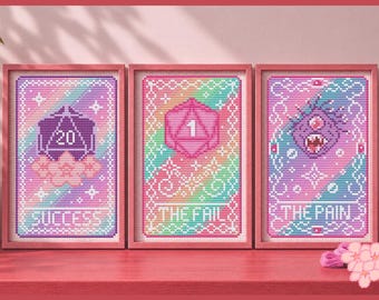 May include: Three framed cross-stitch patterns in pink frames. The left shows a purple 20-sided die with the text SUCCESS. The center shows a pink 20-sided die with the number 1 and the text THE FAIL. The right shows a monster with the text THE PAIN.