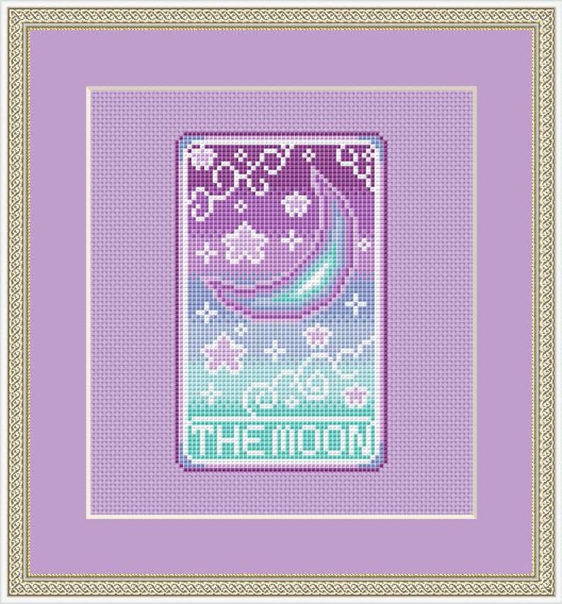 May include: Framed cross-stitch artwork with a celestial theme. It depicts a crescent moon, stars, and clouds in purple, teal, and white. The text "THE MOON" is at the bottom. The artwork is framed in a gold and purple frame, suitable for home decor.