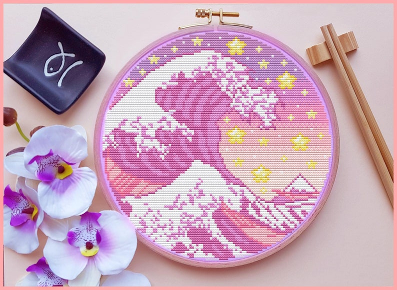 May include: A pink and yellow cross-stitch embroidery of the Great Wave off Kanagawa, a famous Japanese woodblock print by Hokusai, in a round wooden embroidery hoop.