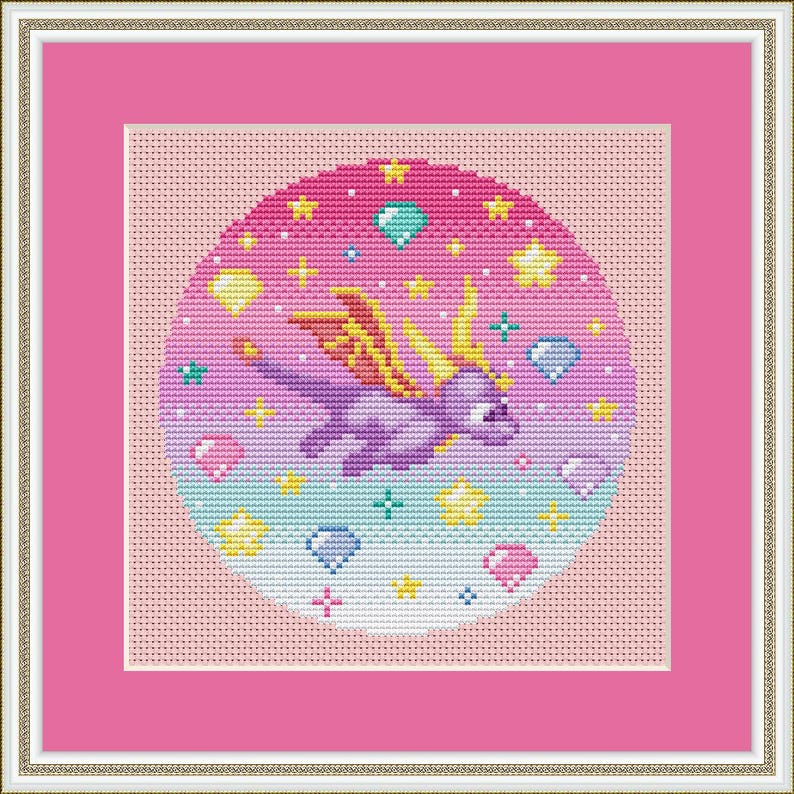 May include: Cross-stitch art of a purple dragon with yellow wings, surrounded by stars, gems, and hearts. The design is set against a gradient pink and blue background, framed in pink and a gold-colored border.