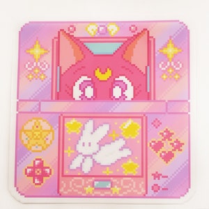 May include: A pink and purple pixel art design of a handheld video game console with a pink cat character on the screen. The game features a white bunny character with wings and stars.