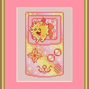 May include: Cross-stitch art of a retro handheld game console featuring a smiling yellow creature with orange accents. The design includes a butterfly, circles, and decorative elements in shades of yellow, orange, and pink, framed in gold.