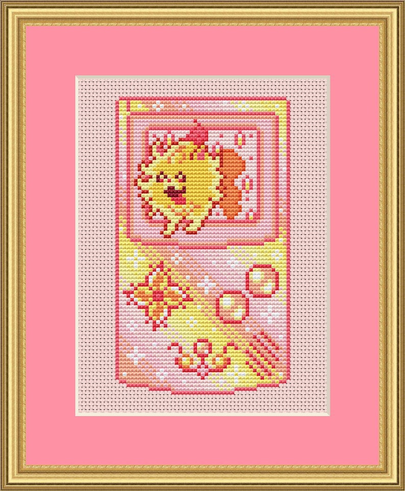 May include: Cross-stitch art of a retro handheld game console featuring a smiling yellow creature with orange accents. The design includes a butterfly, circles, and decorative elements in shades of yellow, orange, and pink, framed in gold.
