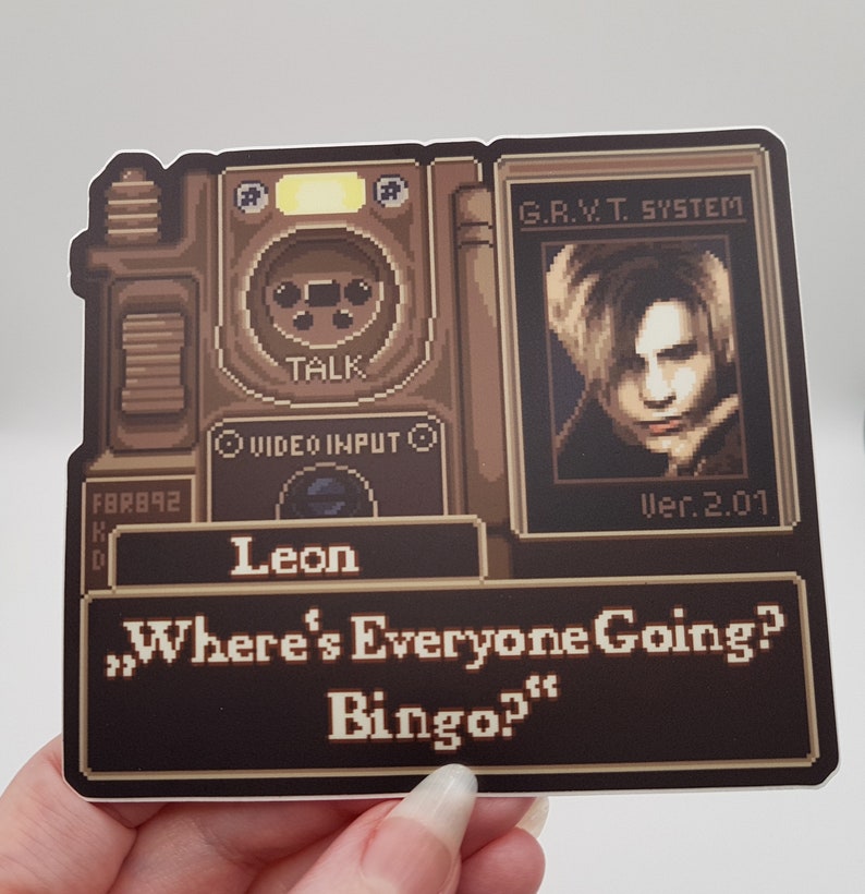 Peut inclure: Une image pix&eacute;lis&eacute;e d'un personnage de jeu vid&eacute;o, Leon, du jeu Resident Evil 2. L'image est dans le style d'une console de jeu vid&eacute;o r&eacute;tro. Le texte "Where's Everyone Going? Bingo?" est affich&eacute; &agrave; l'&eacute;cran.
