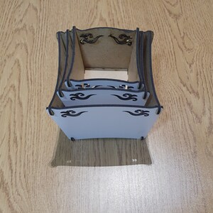 May include: A set of three wooden boxes with intricate black wave designs. The boxes are stacked on top of each other and are made of a light brown wood.