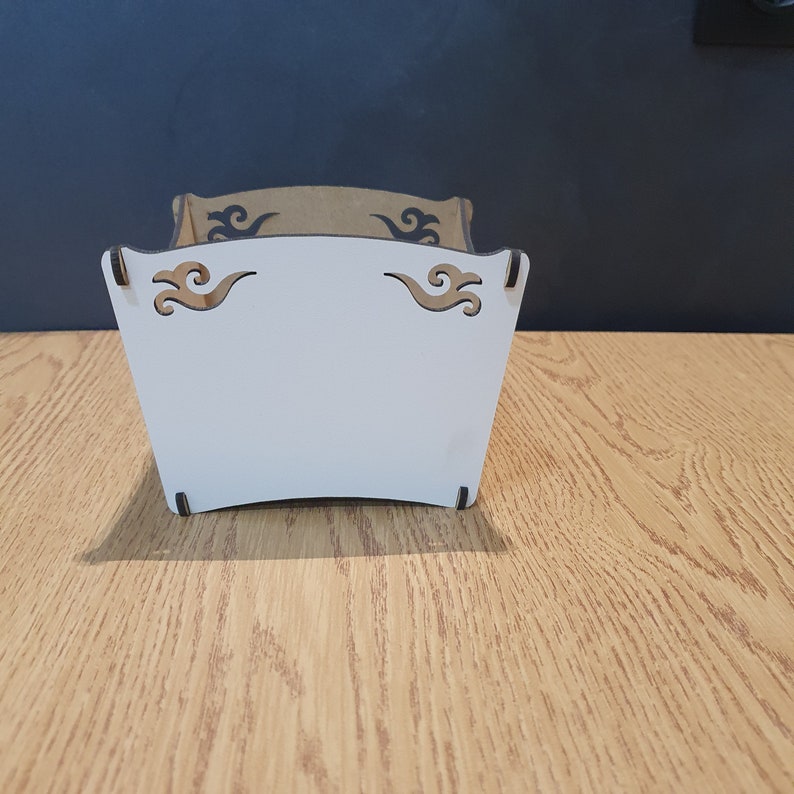 May include: White wooden box with a decorative design of stylized waves. The box has a white interior and is made of wood.