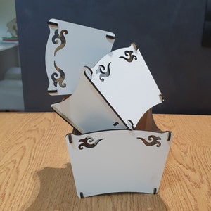 May include: White wooden planter with a decorative design. The planter is made of three pieces that fit together. The planter is empty and ready to be filled with plants.