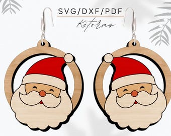 Op de afbeelding: Een paar houten oorbellen met een rond ontwerp met een cartoon gezicht van de kerstman. De oorbellen zijn bruin met zwarte contouren en hebben zilveren haakjes.