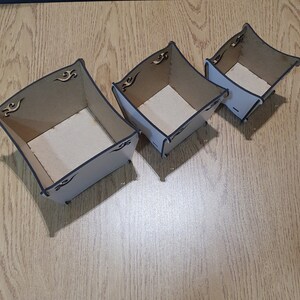 May include: Three wooden boxes with decorative cutouts, nested together in descending size. The boxes are made of light brown wood and have a white interior.