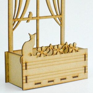 May include: A wooden window box with a cat silhouette and flower cutouts. The box is made of unfinished wood and has a rustic look.