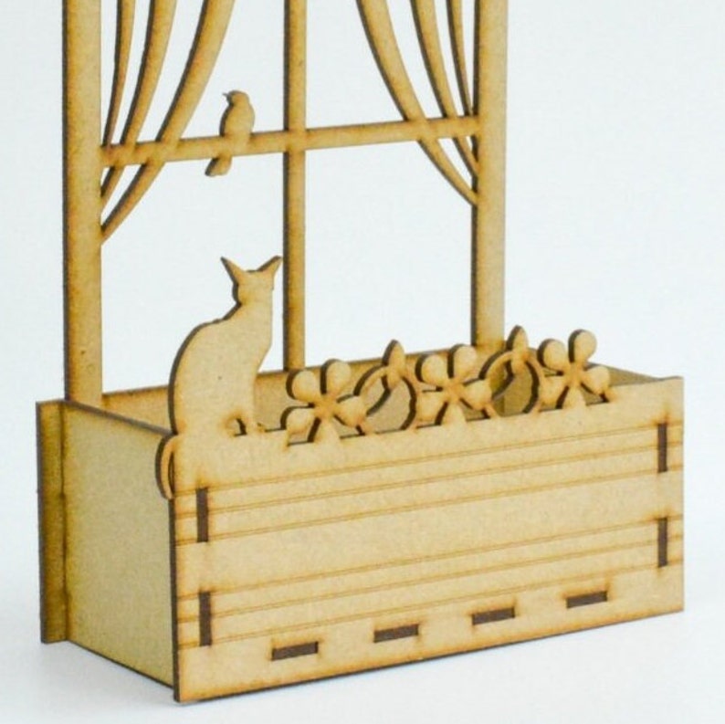 May include: A wooden window box with a cat silhouette and flower cutouts. The box is made of unfinished wood and has a rustic look.