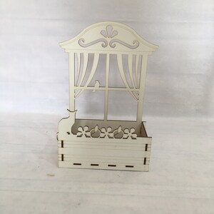 May include: White wooden planter shaped like a window with a cat and bird silhouette. The planter has a decorative top and a window with curtains. The planter has a small box at the bottom with a decorative flower design.
