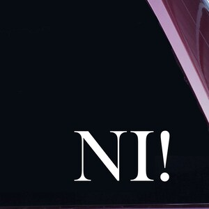 Pode incluir: Adesivo de vinil branco com o texto "NI!" em um fundo preto. O adesivo é aplicado em uma janela de carro vermelha.